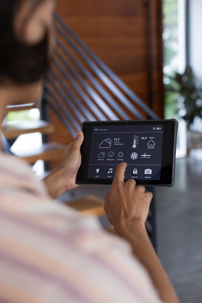 Vertical of hands of biracial man at home using tablet with smart home interface, copy space